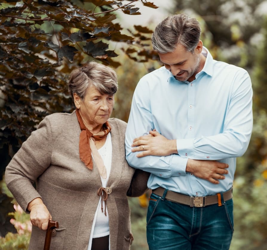 Worried grey senior lady with walking cane in the garden with her son