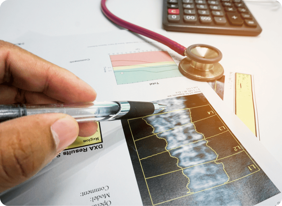 iStock-1178124526-modified Closeup of hospital documents, with stethoscope and calculator. Doctor pointing pen to bone density screening results.