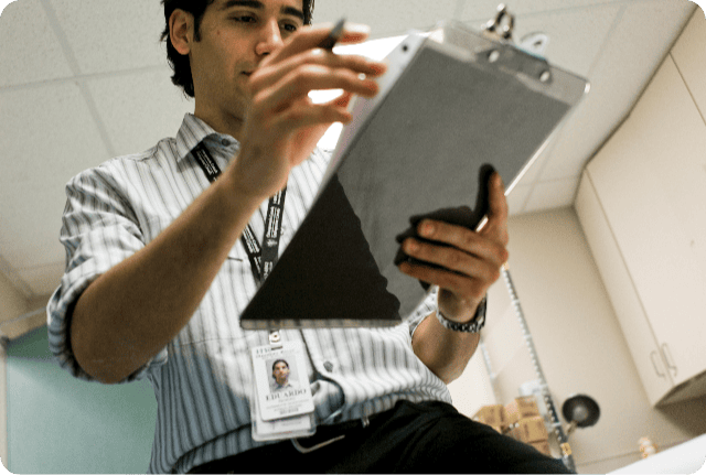 img01-modified Nurse in an exam room reviewing documents on a clipboard